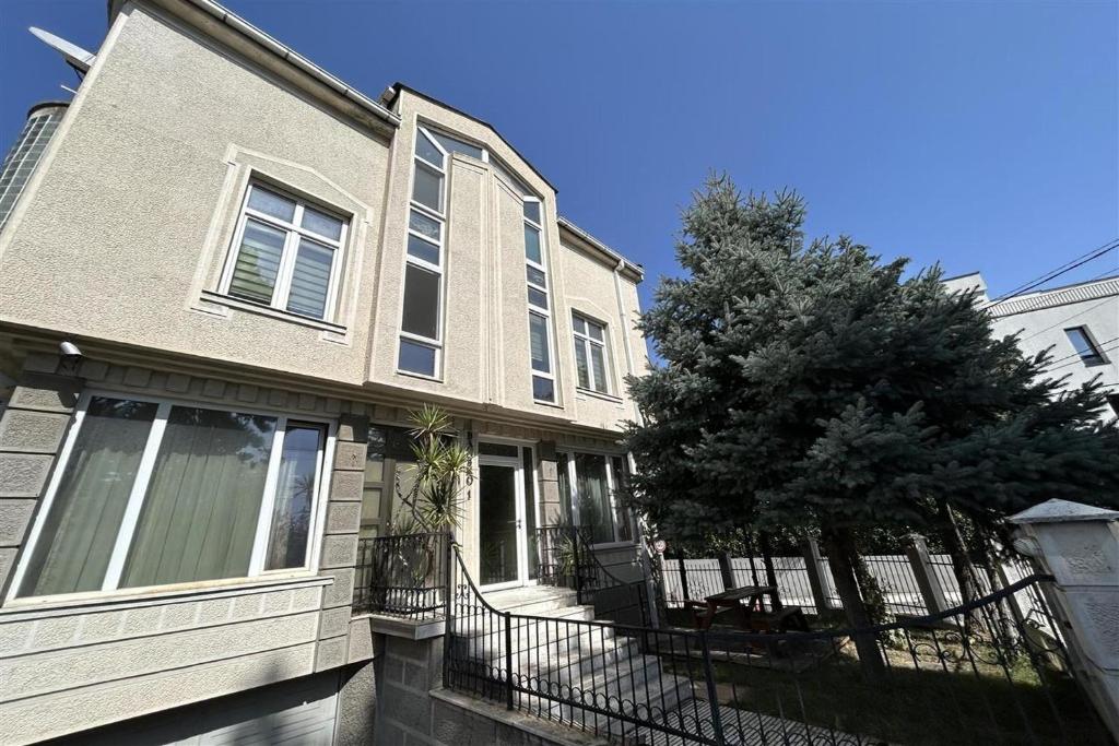 a house with a fence and a tree in front of it at Peaceful apartment with yard and parking in Skopje