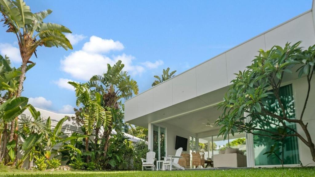 a white house with white chairs and trees at Casa Lux- Infared Sauna and heated magnesium pool in Kingscliff