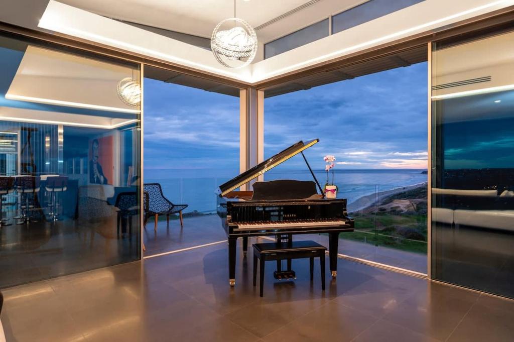 un piano en una habitación con vistas al océano en Luxe Haus - Exceptional Views NobleBNB, en Moana
