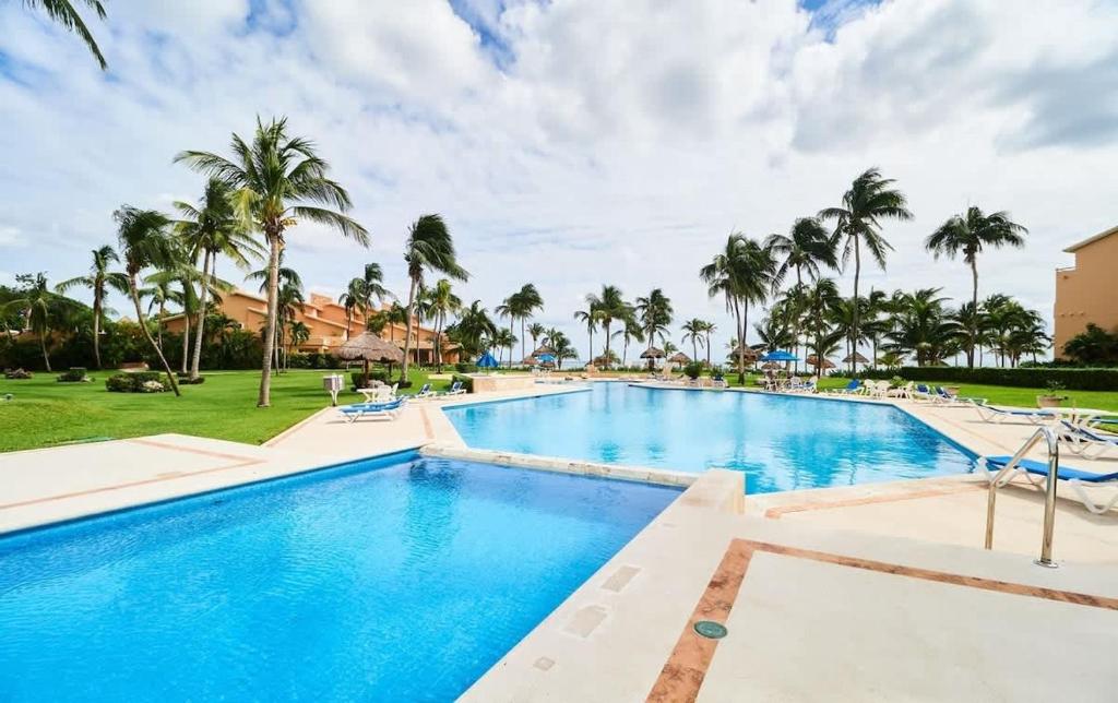 a pool at the resort with palm trees at BeachFront Appt w/Amazing Pool in Puerto Aventuras in Puerto Aventuras