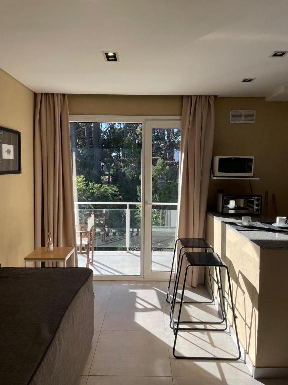 a room with a bed and a kitchen with a balcony at Nexo Playa Depto 6 in Valeria del Mar