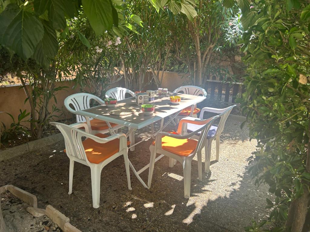 une table et des chaises assises sous un arbre dans l'établissement **Gruissan - T2 Cabine Mezzanine - Côté Village - 6 pers - Parking Privé - Proche Plages** - FR-1-796-63, à Gruissan