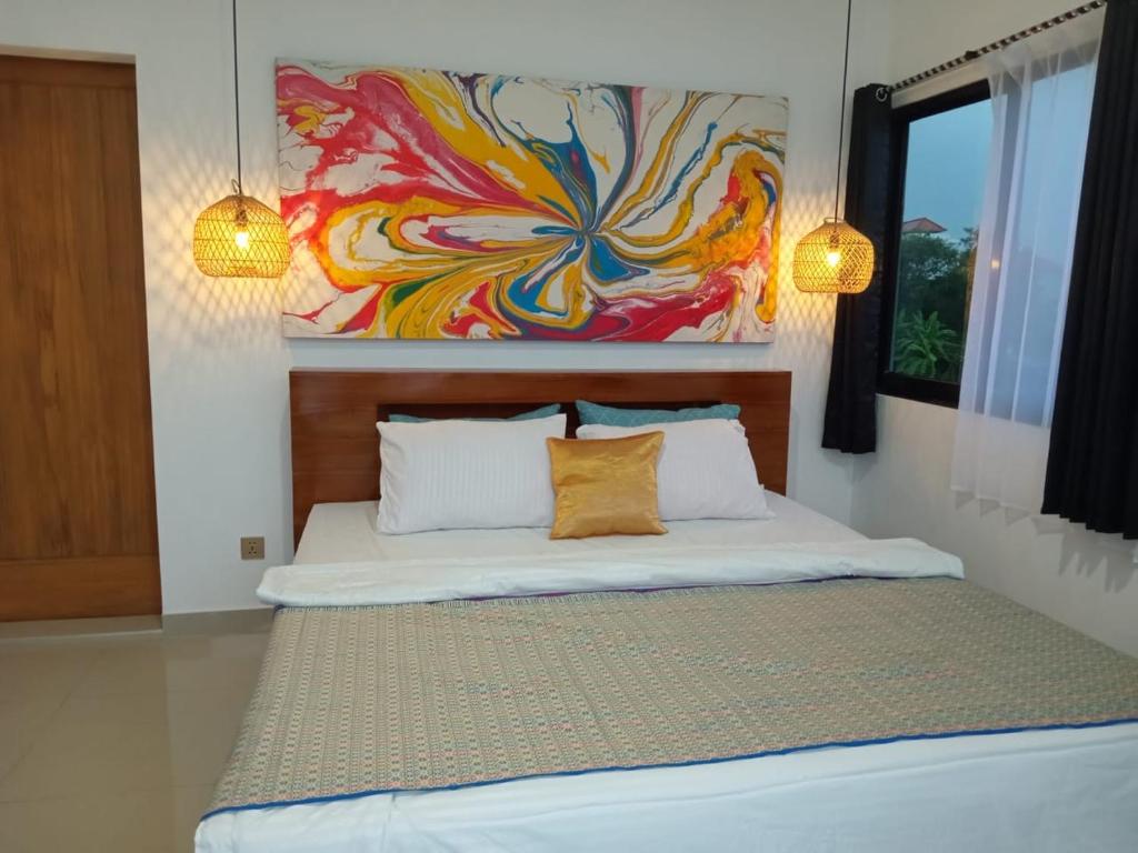 a bedroom with a bed with a painting on the wall at South Island Bali -Near Uluwatu in Jimbaran