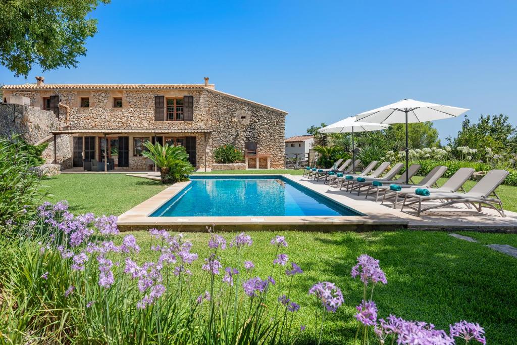 a villa with a swimming pool and a garden with purple flowers at Pontarro in Pollença