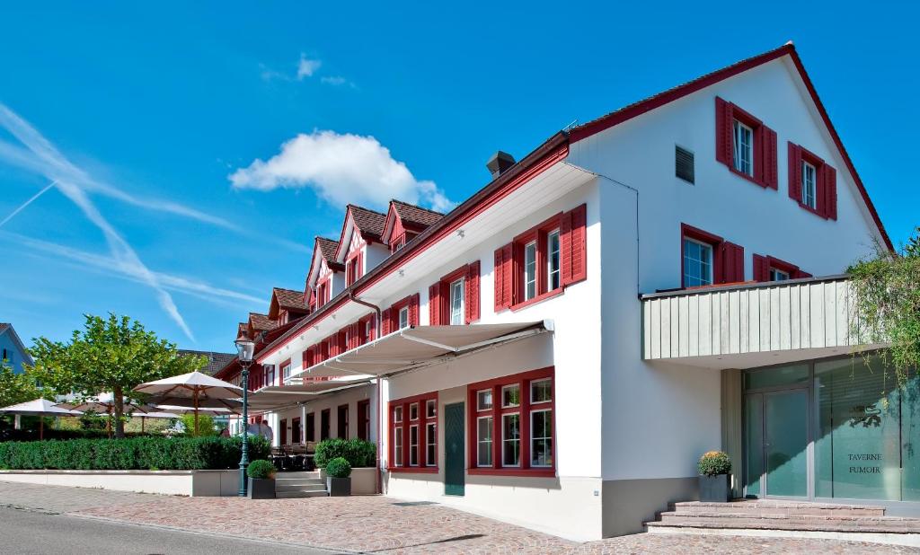 ein weißes Gebäude mit roten Akzenten auf einer Straße in der Unterkunft Hotel-Restaurant Löwen in Dielsdorf