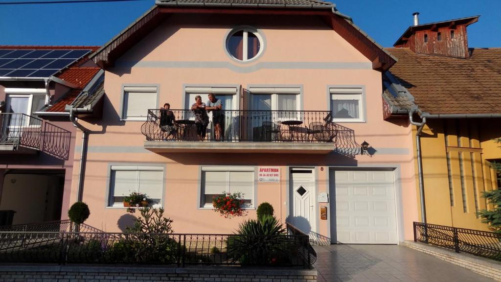 un groupe de personnes debout sur le balcon d'une maison dans l'établissement Gere Apartment House, à Harkány