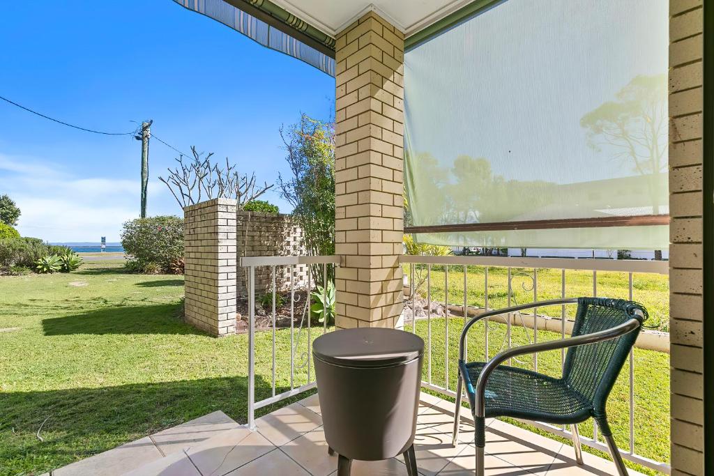 a patio with a chair and a trash can at Dolphin View on South Esplanade in Bongaree