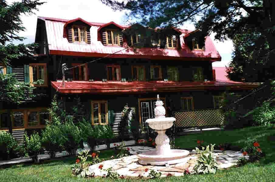 a large house with a fountain in front of it at Auberge du Lac Morency in Saint-Hippolyte