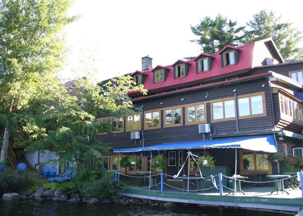 a large wooden house on the water next to a river at Auberge du Lac Morency in Saint-Hippolyte