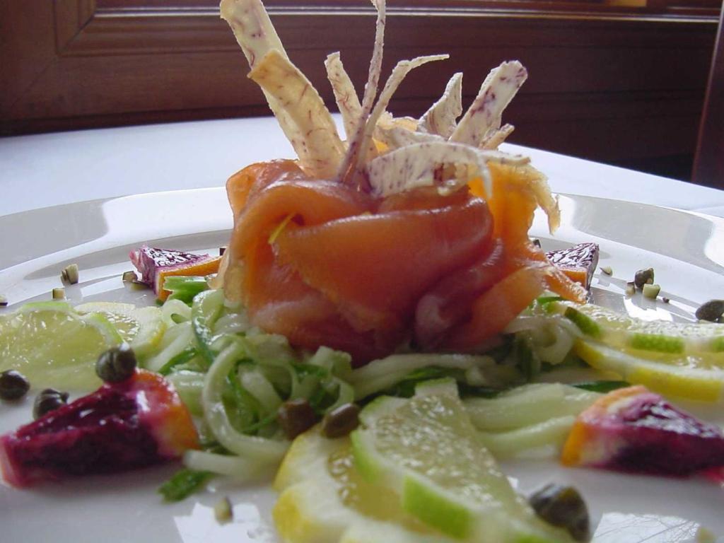 a white plate with a salad on a table at Auberge du Lac Morency in Saint-Hippolyte