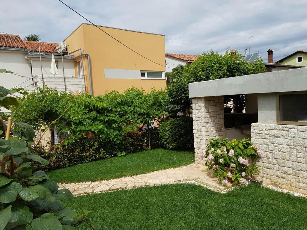 un patio trasero de una casa con un patio con césped verde en Apartment Lency, en Novigrad Istria