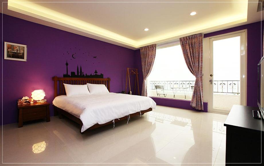 a bedroom with purple walls and a large bed at Color Sea B&B in Dawu