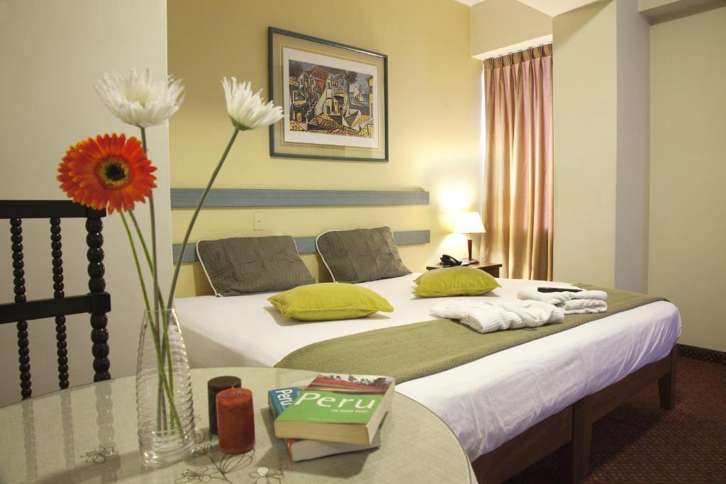 a hotel room with a bed and a vase of flowers at Kamana Hotel in Lima