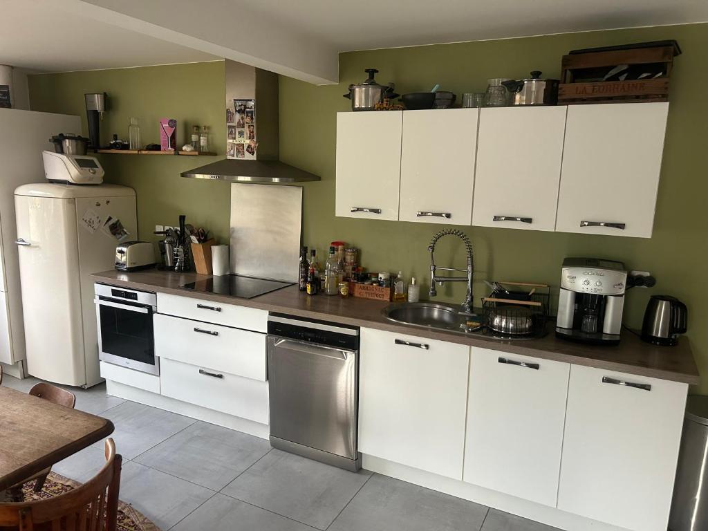 a kitchen with white cabinets and stainless steel appliances at Chambre paisible proche Centre Ville in Saint-Yrieix-sur-Charente