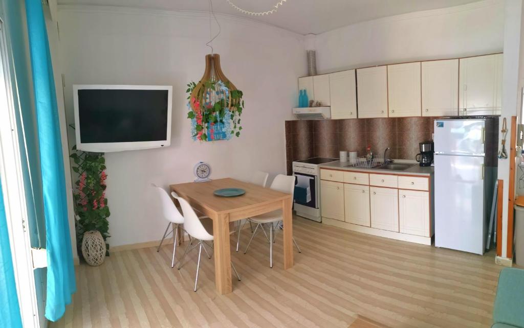 Una pequeña cocina con una mesa y un refrigerador. en Athena Apartment, en Nea Peramos
