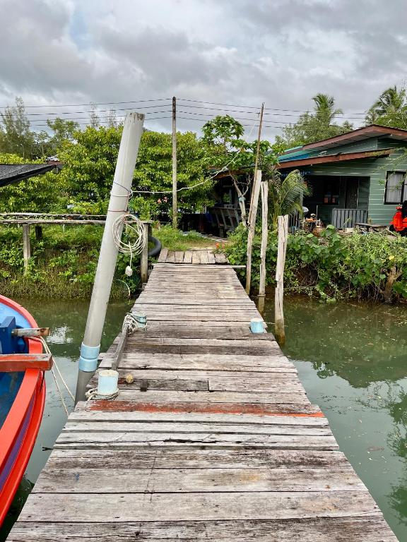 a wooden dock in the water next to a house at The Summer Guesthouse in Ban Khlong Son