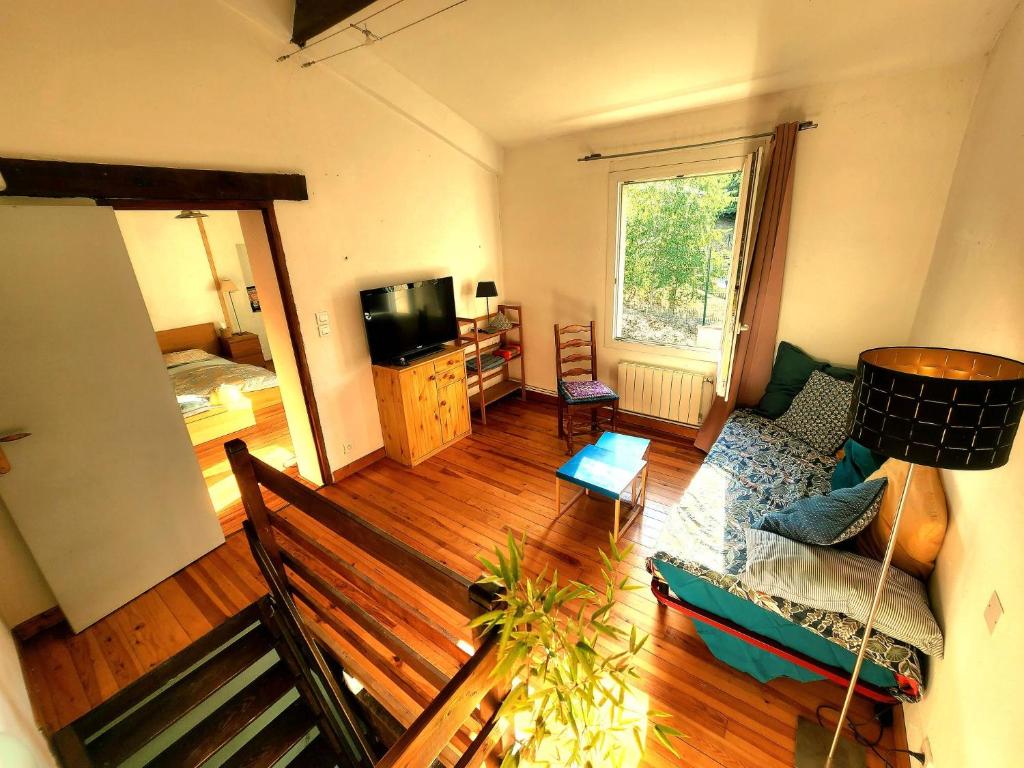 a living room with a couch and a television at Charming brickyard cottage near a lock in Ayguesvives