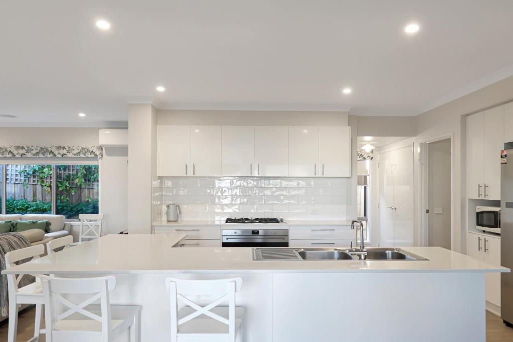 a kitchen with white cabinets and a large white island at The panorama retreat- sleeps 12, aircon, brand new, great multifamily stay, beach, wineries, golf in Portarlington