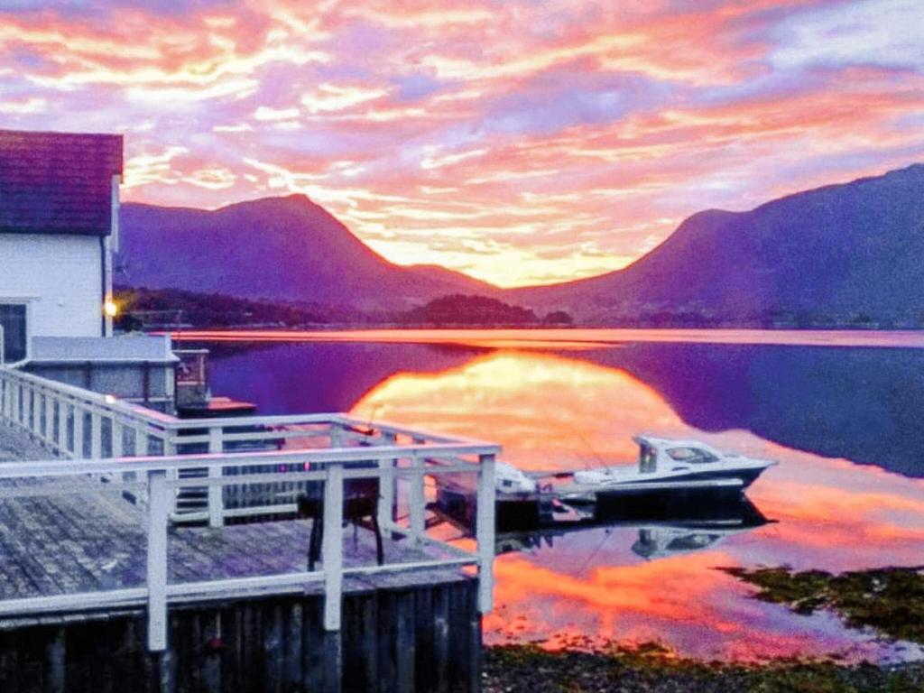 a boat is docked at a dock on a lake at 9 person holiday home in GURSKØY-By Traum in Kjellsund
