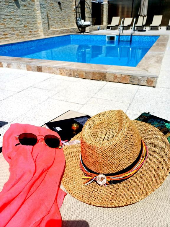 a straw hat and sunglasses next to a hat and a towel at SunRiviera Mamaia Nord in Mamaia Sat/Năvodari