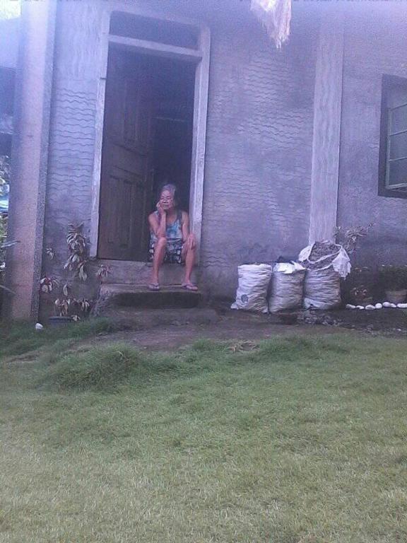 a woman sitting on the porch of a house at Belmoro Transient House in Bacacay