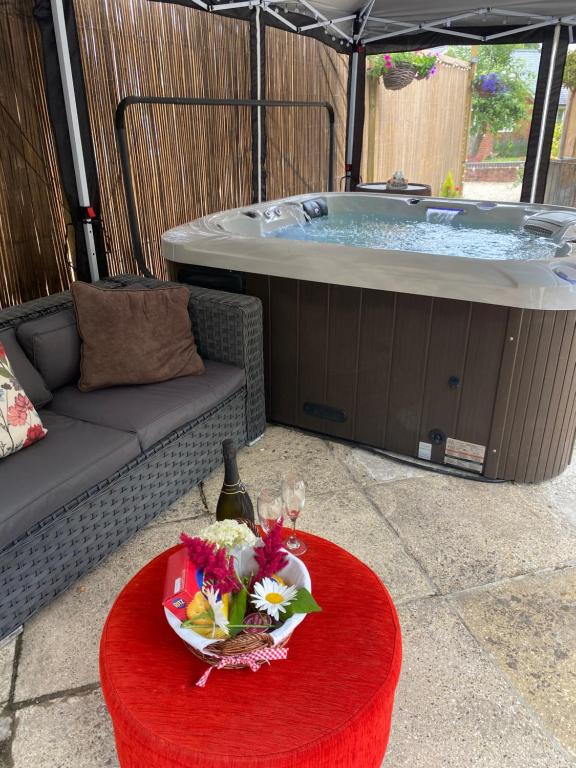 a jacuzzi tub with a table with a bowl of flowers at Secluded Retreat for Family and Friends with Private Hot Tub Dorset in Horton
