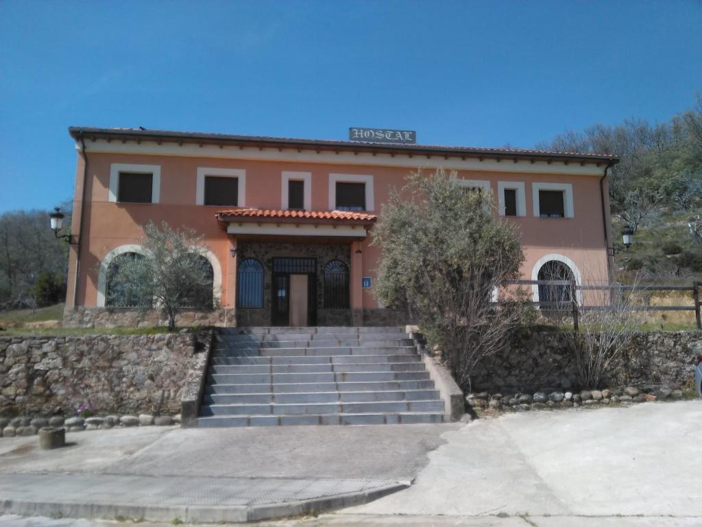 una casa con escaleras frente a un edificio en Hostal Miraflor de las Cadenas, en Cuacos de Yuste