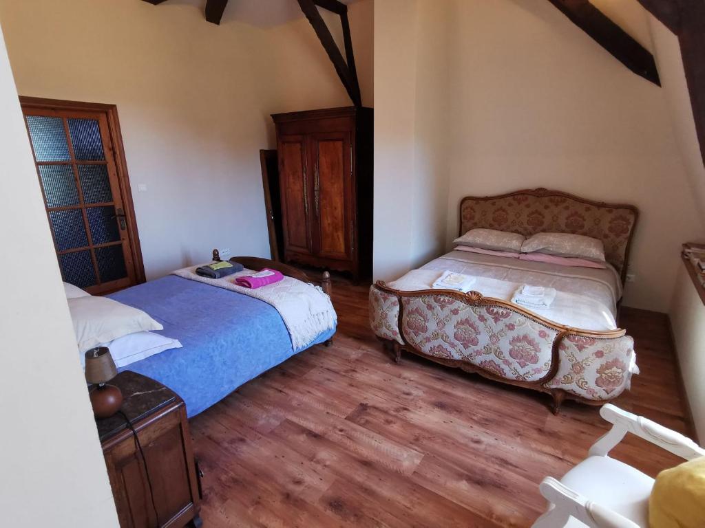 1 Schlafzimmer mit 2 Betten und Holzboden in der Unterkunft Le Crévy - Les Ecuries - 14 pers in La Chapelle-Caro