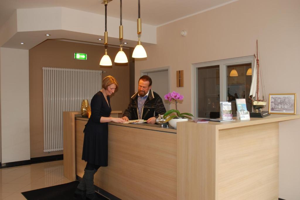 a man and a woman standing at a counter at Apartment Hotel Rüther in Papenburg