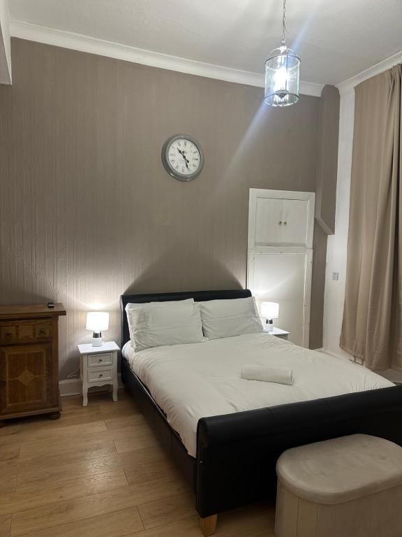 エディンバラにあるDouble room with garden In The Heart of Edinburghの壁に時計が付いたベッドのある寝室