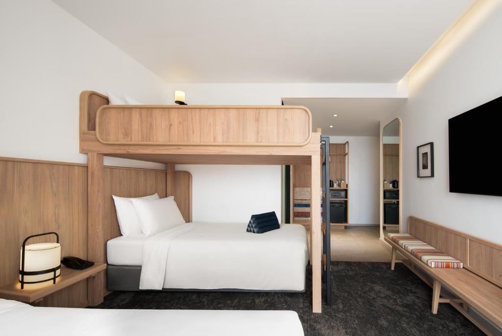 A family-style room with a raised bunk above a double bed, bench seating, and a wall-mounted TV.