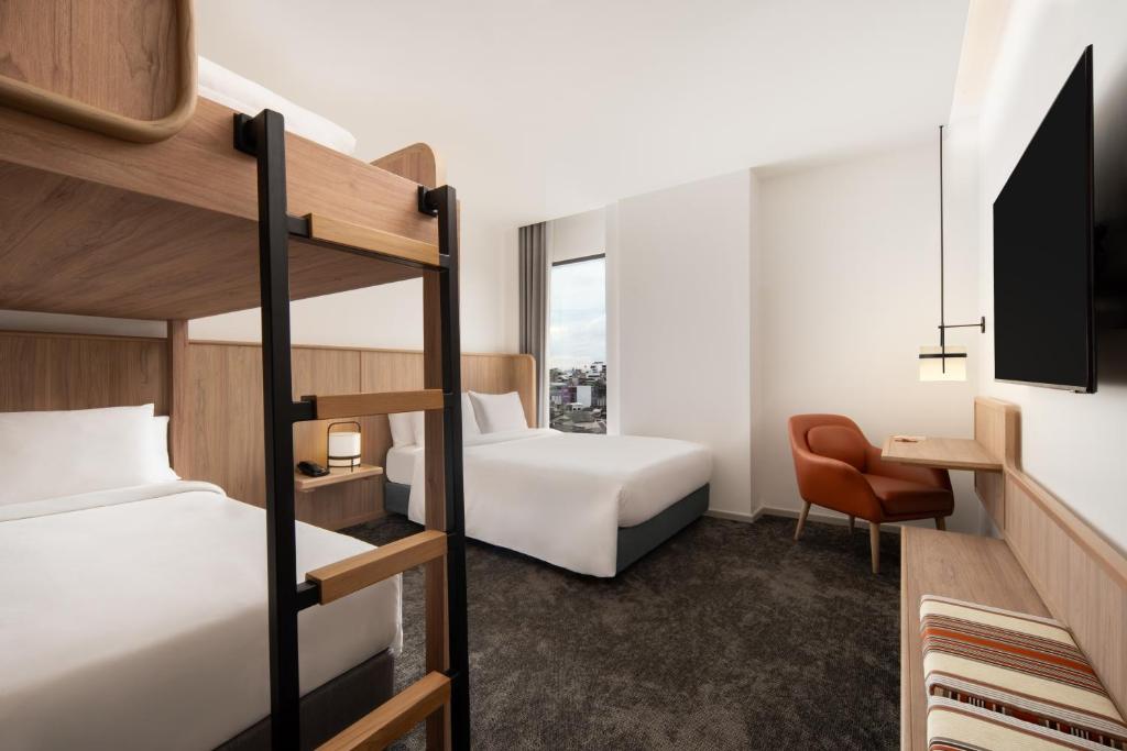 A multi-bed room with bunk beds, separate beds, a compact desk, and a city-facing window.