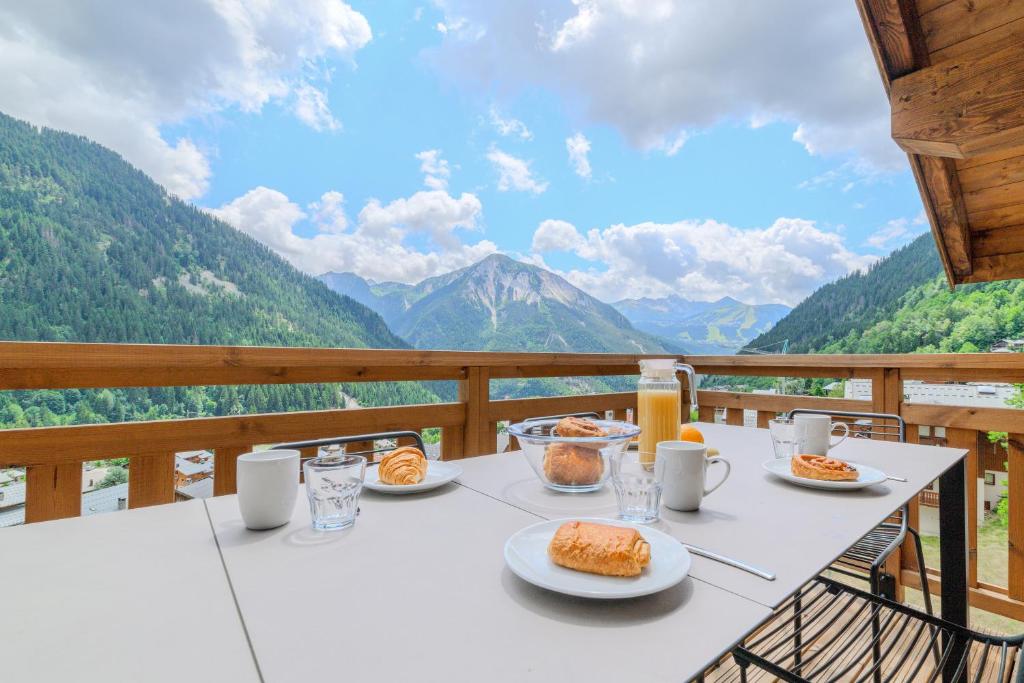 una mesa con platos de comida en un balcón con montañas en TERRESENS - L'Etoile de la Vanoise, en Champagny-en-Vanoise