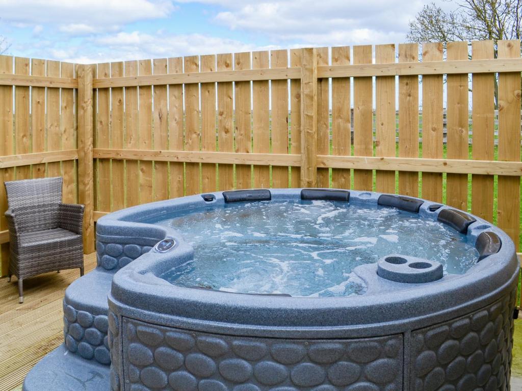 a hot tub in a yard next to a wooden fence at Oxley Cottage in Orby