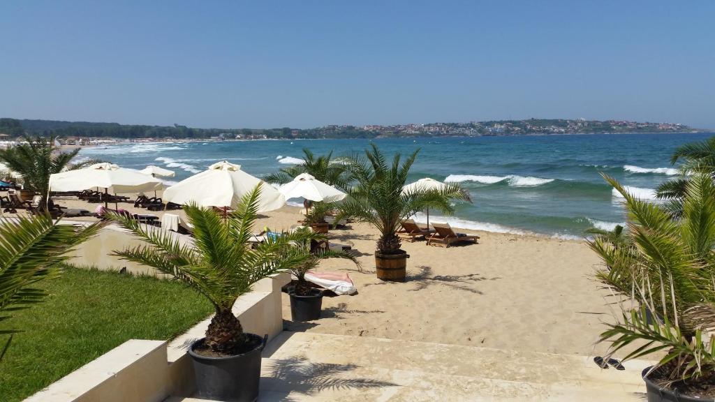 ソゾポルにあるGITEA Sand Lilies Apartmentsのヤシの木と傘と海のビーチ