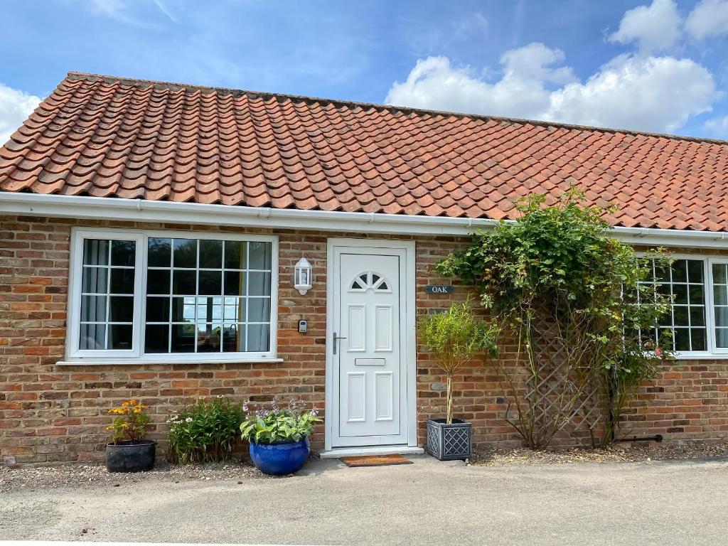 una casa de ladrillo con puerta blanca y techo rojo en Oaks - Uk47372, en Burgh le Marsh