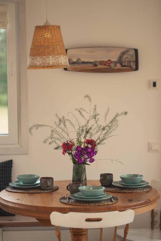 a table with plates and a vase of flowers on it at Hygge House Hiiumaa in Hiiumaa