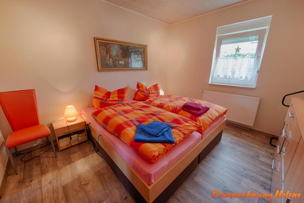 een slaapkamer met een bed, een stoel en een raam bij Helene in Hüttenrode