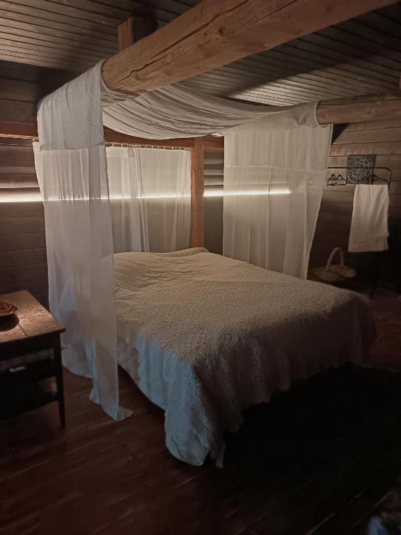 a bedroom with a canopy bed with white curtains at Wallilan Yliset in Äänekoski