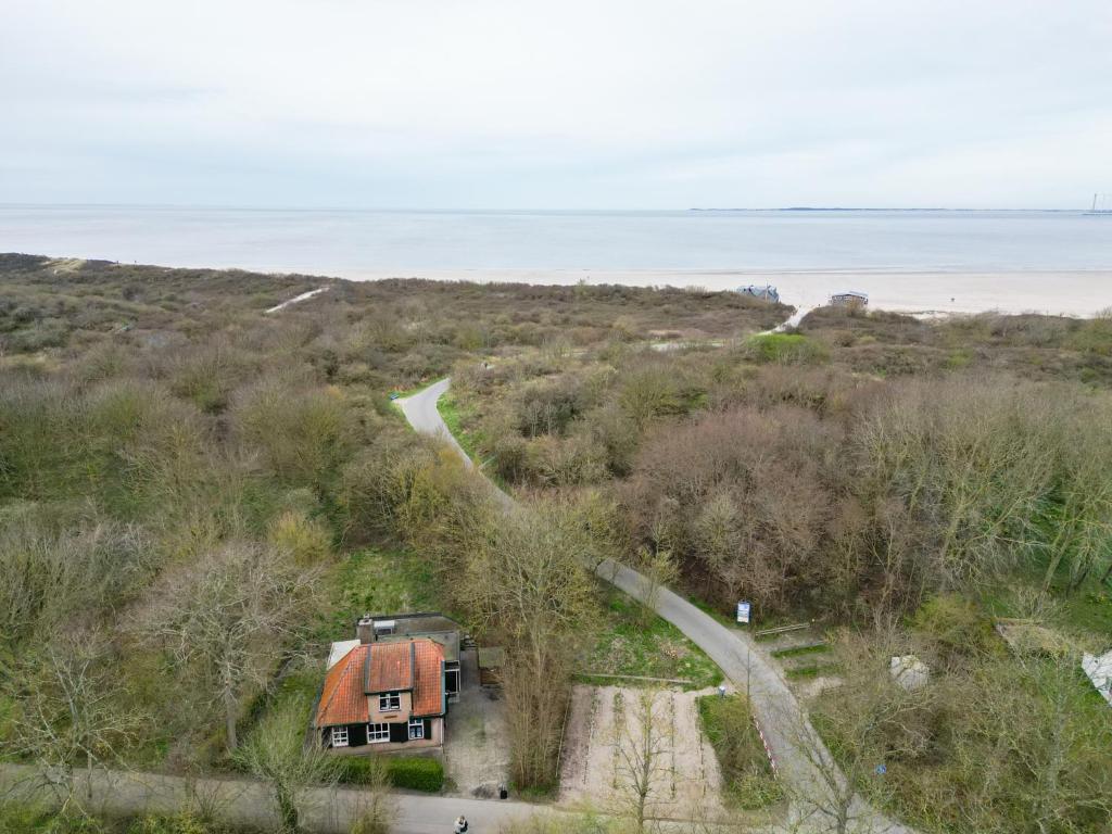 an aerial view of a house on a hill next to the ocean at Vakantiewoning Hosa Semna in de duinen van Vrouwenpolder in Vrouwenpolder