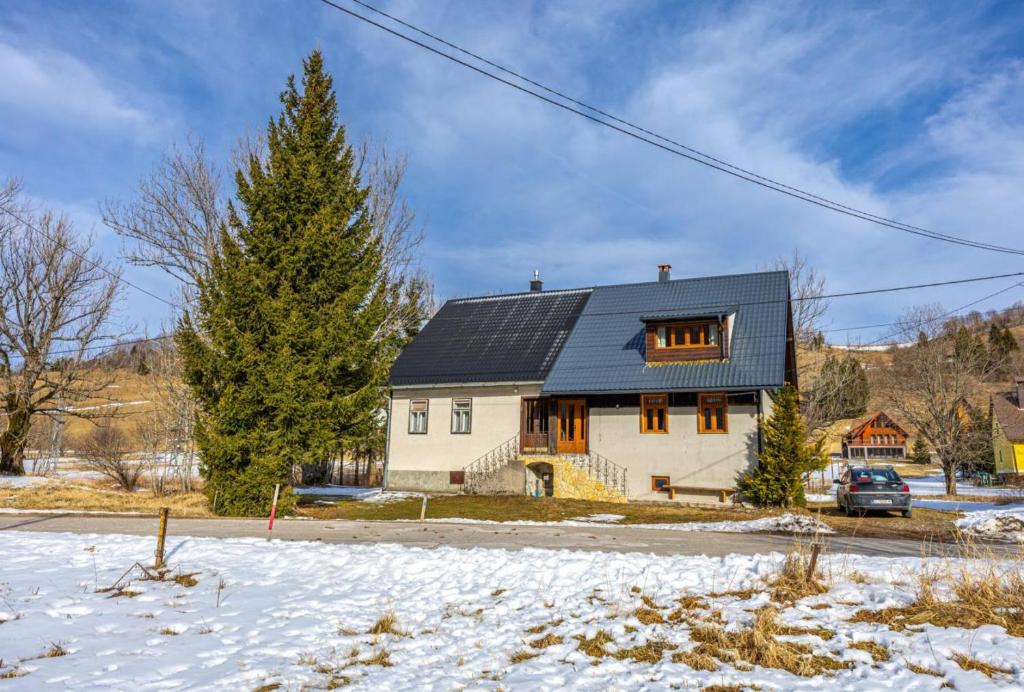 a white house with a black roof in the snow at D&D kuća za odmor in Begovo Razdolje