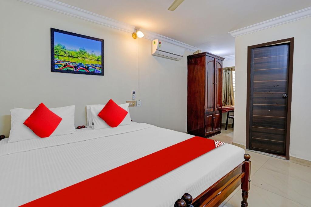 a bedroom with a large white bed with red pillows at Hotel O Le Fort in Trivandrum