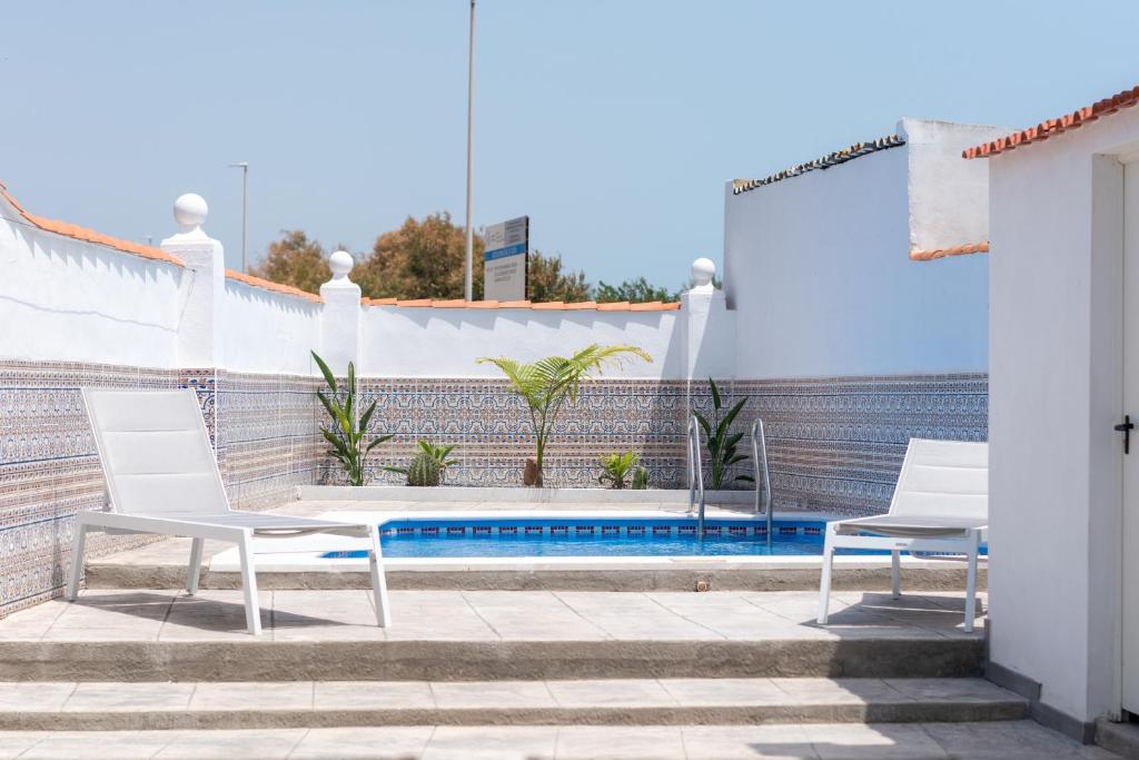 a patio with two white chairs and a swimming pool at Global Properties, Deslumbrante casa en la playa de Sagunto in Sagunto