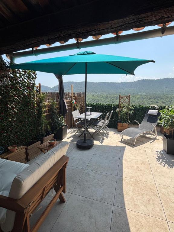 a patio with an umbrella and a table and chairs at KATELL BeachHouse in Bagnols-en-Forêt
