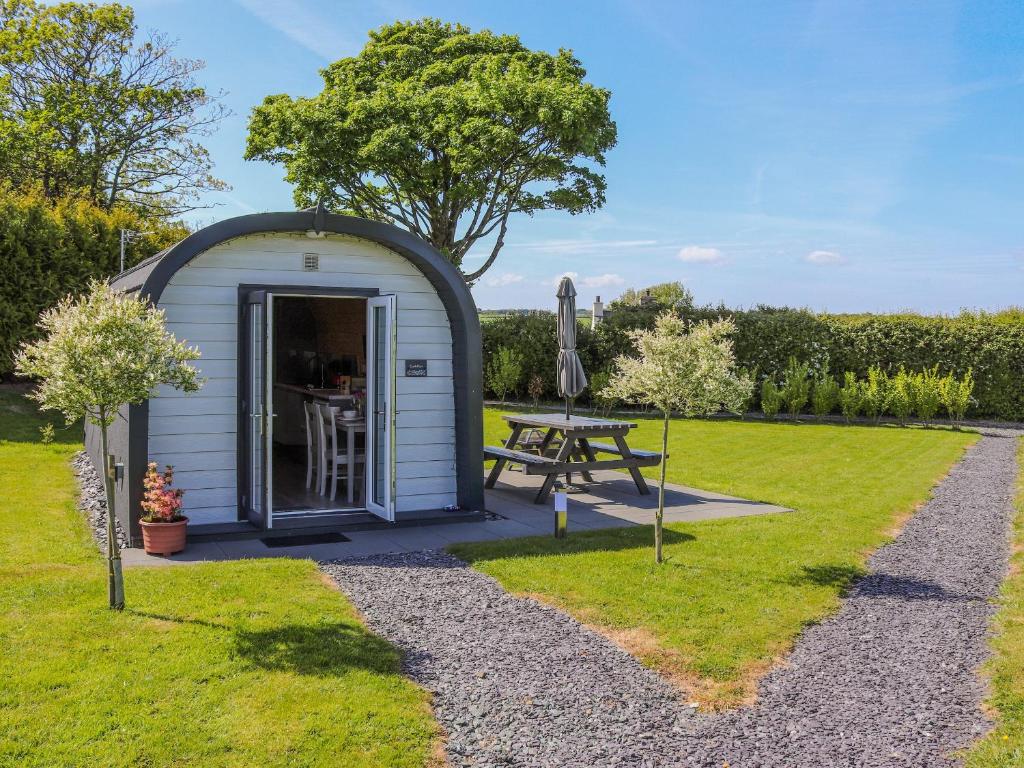 a small shed with a picnic table in the grass at Cuddfan - Uk49673 in Brynsiencyn