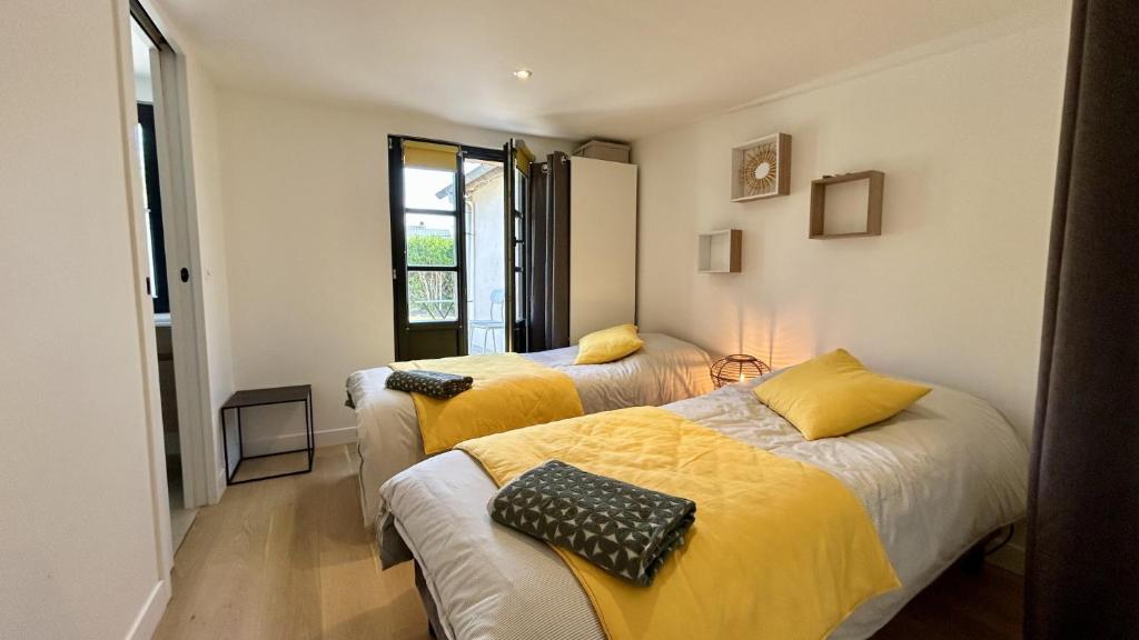 two beds in a room with yellow sheets at Hozanna chic & charme in Le Crotoy