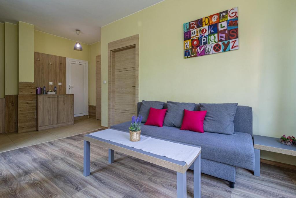a living room with a blue couch and pink pillows at My Space Deluxe One Bedroom Apartment in Sofia