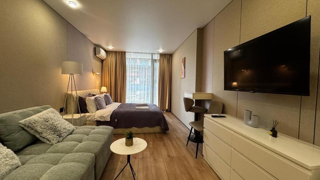 Una sala de estar con un sofá, una cama y un televisor. en Sunset Studio Apartment, en Batumi