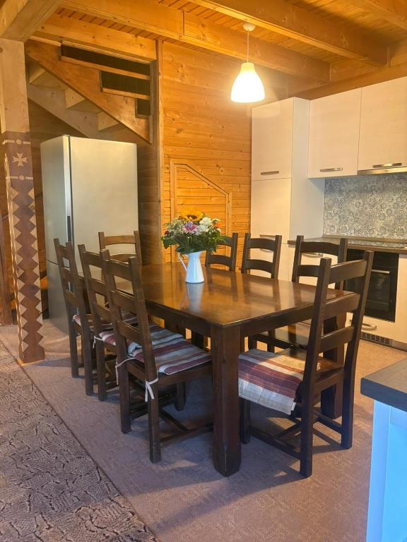 a wooden dining room table with chairs and a refrigerator at Forest & Lake House in Dumbrăviţa