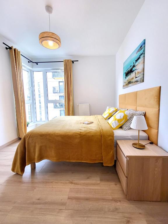 Un dormitorio con una cama grande con una manta amarilla. en Ursus Premium Apartments, en Varsovia